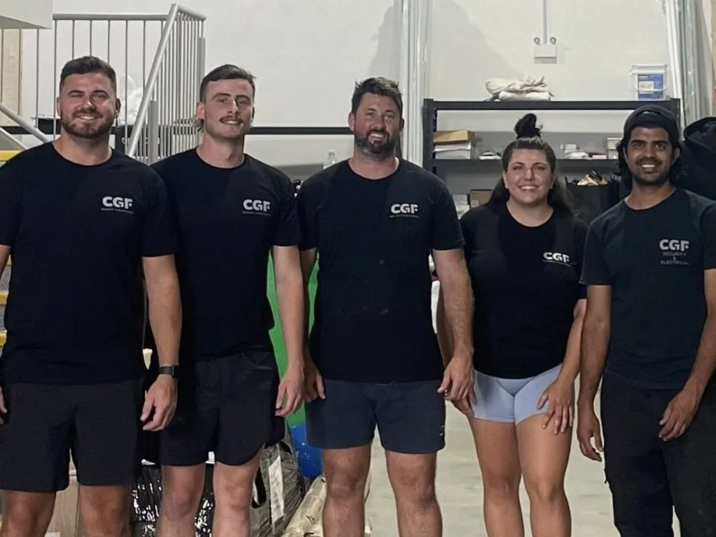 Five members of the CGF team in matching CGF shirts, smiling in their warehouse